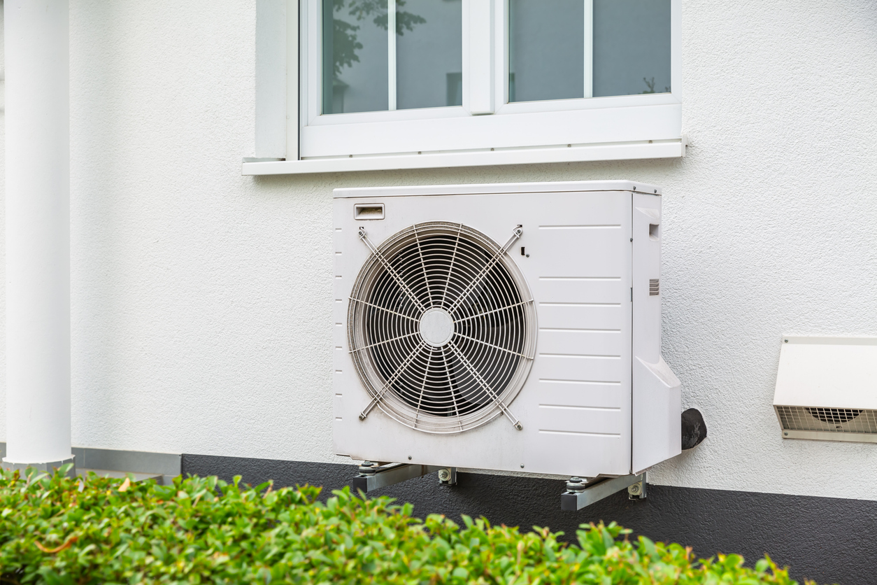 Outdoor air-source heat pump unit mounted on home wall. Energy-efficient HVAC system in Seattle