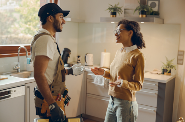 Technician discussing AC maintenance with homeowner in kitchen
